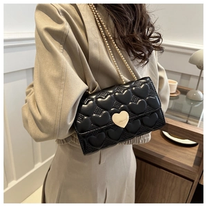Détail du sac bandoulière noir avec matelassage en cœur et fermoir en métal doré en cœur