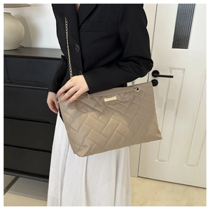 Detailansicht der khakifarbenen Stepptasche mit goldener Kette und Metall-Logo-Plakette