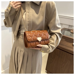 Détail d'un sac marron avec surpiqûres en cœur et fermoir métallique argenté en cœur