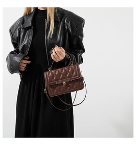 Detail showing dark brown quilted handbag with gold metal clasp on a model