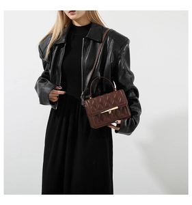 Detailed close-up of brown quilted crossbody bag with golden lock and chain on model