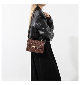Close-up of brown quilted leather bag with gold metal buckle and elegant crossbody strap