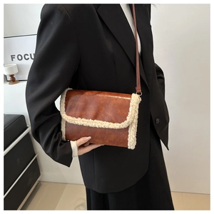 Close-up of retro brown faux leather crossbody bag with white shearling trim detail