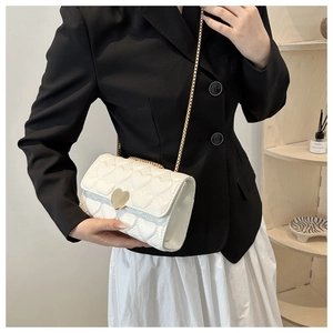 Détail du sac bandoulière blanc matelassé avec fermoir cœur doré sur modèle