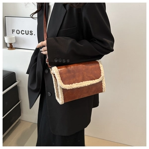 Detail of brown vintage leather crossbody bag with white faux shearling trim accents