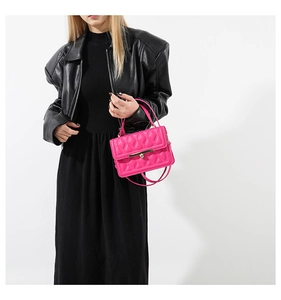 Close-up of hot pink quilted crossbody bag with gold skull detail on black leather jacket