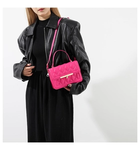 Detail of rose pink quilted crossbody bag with golden clasp on black leather outfit
