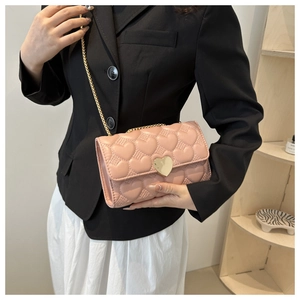 Détail d'un sac à main rose matelassé avec un grand fermoir en métal doré en forme de cœur