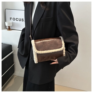 Detail of vintage brown PU leather crossbody bag with white faux shearling trim accents