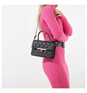 Detail of black quilted crossbody bag featuring elegant gold hardware and metal buckle