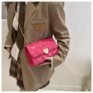 Détail du sac matelassé cœur fuchsia avec fermoir cœur doré sur une veste brune