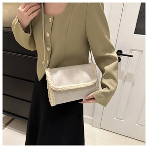 Close-up of cream white fleece-trimmed leather crossbody bag on elegant model