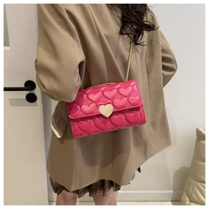 Gros plan d'un sac bandoulière rose matelassé cœur avec fermoir cœur en métal doré