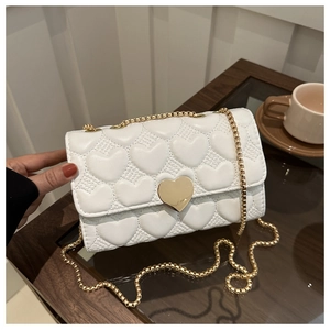 Détail du matelassage en cœur blanc et du fermoir en métal doré en forme de cœur du sac