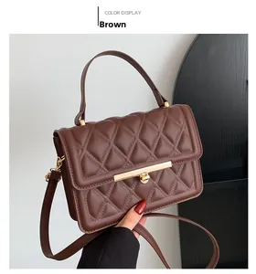 Detail of a brown quilted leather crossbody bag with a sleek gold metal lock and handle