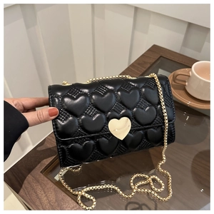 Détail d'un sac bandoulière matelassé noir avec motif de cœur et fermoir doré en cœur