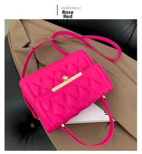 Detail of rose red quilted crossbody bag with gold metal trim and turn-lock closure