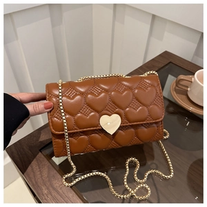 Détail du sac marron avec matelassage cœur, fermoir cœur doré et bandoulière chaîne