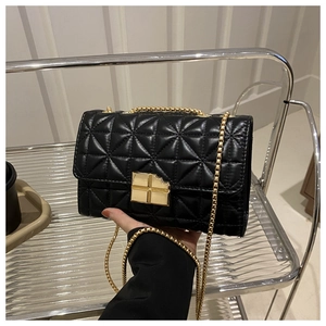 Détail du fermoir tournant doré sur un petit sac bandoulière noir à losanges matelassés
