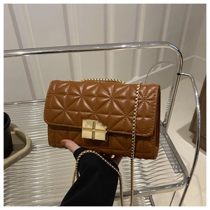 Détail d'un sac bandoulière marron matelassé avec une chaîne dorée et un fermoir carré chic