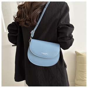 Sacoche selle minimaliste en cuir bleu clair avec bandoulière portée par un mannequin