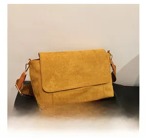 Detail of mustard suede tote bag featuring a large flap cover and brown wide shoulder strap