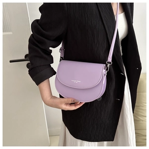 Détail du sac besace lavande en cuir avec texte imprimé blanc et fine bandoulière réglable