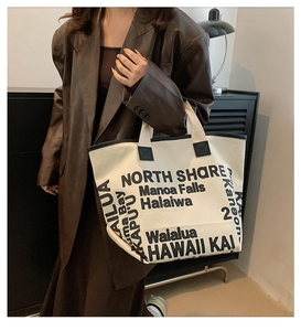 Close-up of large canvas tote bag with black lettering and high-capacity structure