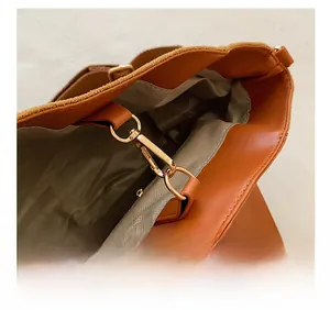 Detail of brown tote bag showing gold metal clasp and premium herringbone fabric lining
