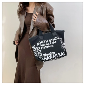 Macro view of black canvas tote bag with white North Shore lettering and durable straps