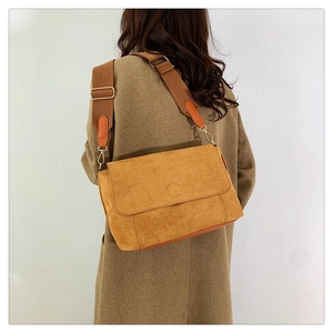 Detail of ginger suede crossbody bag showing wider woven strap and gold metal hardware