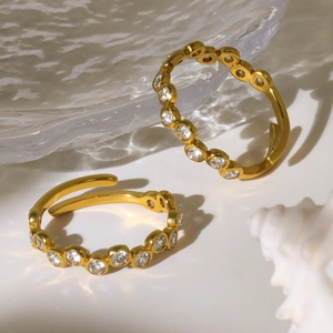Minimalist 18K gold plated titanium rings with white zircon stones on a glass tray