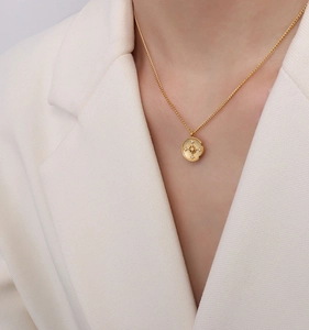 Detail of a vintage gold starburst compass pendant necklace worn with an elegant suit