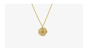 Close-up of golden irregular coin pendant with starburst engraving and zircon inlay necklace