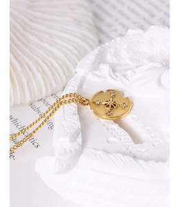 Detailed view of irregular gold compass pendant with zircon star on white plaster block