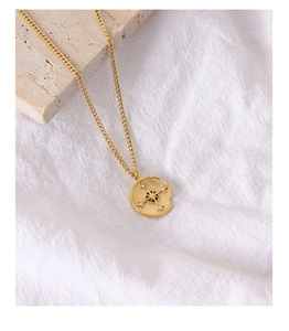 Macro detail of gold star compass coin pendant with zircon inlay on a delicate chain