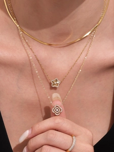 Gros plan d'un ensemble de colliers dorés à plusieurs rangs avec pendentifs étoile et fleur