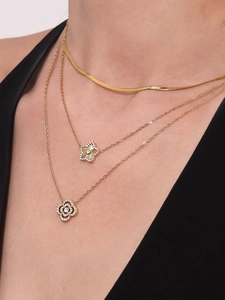Vue détaillée de colliers dorés superposés avec trèfle en zircon et pendentifs en étoile