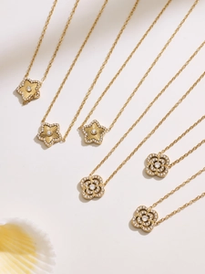 Détail de colliers double couche dorés avec pendentifs étoile et fleur sertis de zircones