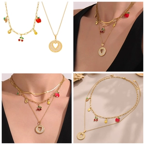 Detalle del collar en capas chapado en oro 18k con dijes de frutas de esmalte y colgante corazón