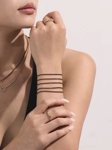 Détail d'un bracelet multicouche à perles noires porté avec des bijoux dorés