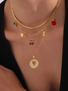 Detalle de collar multicapa chapado en oro 18k con dijes de frutas coloridas y colgante de corazón