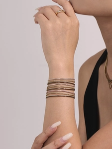 Gros plan de bracelets de tennis superposés en zircons multicolores et plaqués or 18 carats