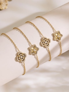 Détail de bracelets dorés avec trèfles et étoiles en zircon sur support soie