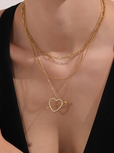 Dettaglio collana a tre strati in oro 18k con catena a graffetta e pendente cuore e freccia
