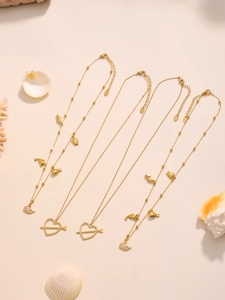 Dettaglio di collane placcate oro 18k con ciondoli a cuore e delfino su conchiglie