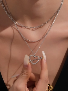 Dettaglio della collana a tre strati con pendente a cuore e freccia e zirconi cubici