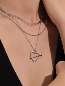 Dettaglio di una collana argentata a tre strati con pendente a cuore e freccia ghiacciato
