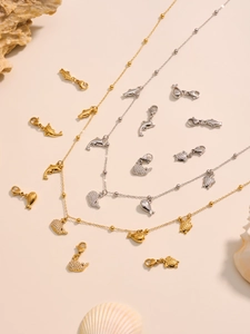 Dettaglio di gioielli marini con pendenti a forma di delfino e tartaruga oro e argento