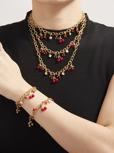 Détail de parure collier et bracelet cerises rouges avec zircons sur chaîne dorée